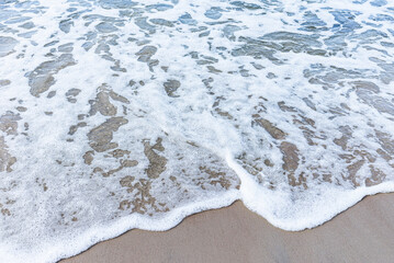 Wave of the sea on sandy beach white foam.Top view of a wave breaking on the sand at the beach. Top view,Copy space.