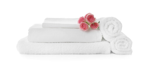 Fototapeta na wymiar Fresh clean towels and bed sheets with roses on white background