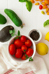 A bowl full of tomatoes, avocado, peppers, lemons and other vegetables