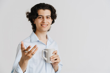 Young brunette man wearing shirt gesturing while drinking coffee