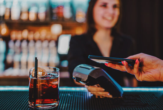 Contactless mobile payment. Payment terminal and smartphone in hands in bar