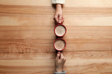 Women with cups of coffee at wooden table, top view