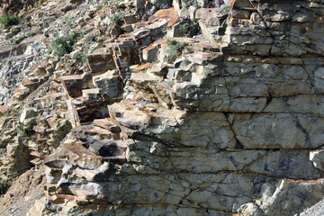 A steep stone wall on the seashore. Rocky shore.