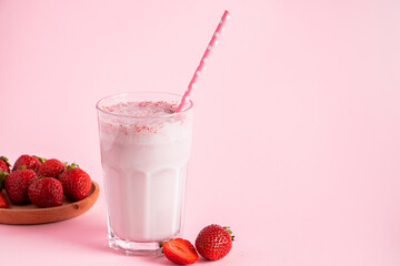 Fresh milkshake with strawberries on pink background. Summer drink with berries in a glass. Place for text.