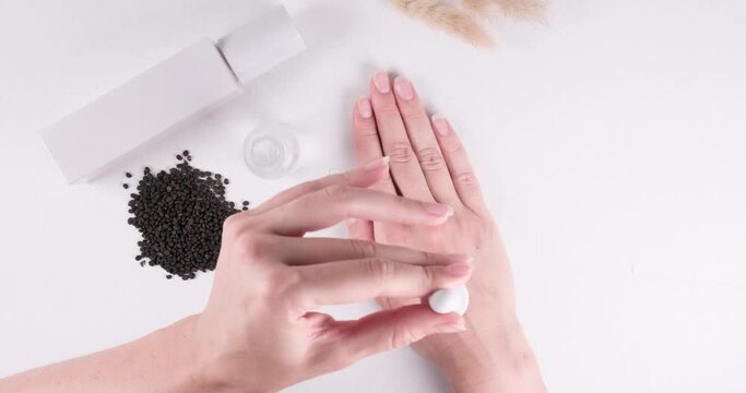 Top down view of woman hands applying serum product with Bakuchiol ingredient.