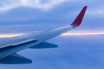 a view from a height above the clouds from the plane's window. part of an airplane wing in the frame