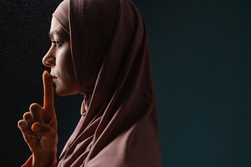 Young muslim woman in hijab showing silence gesture