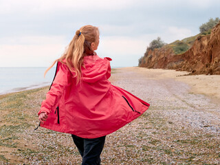 The adventures of alone girl in a pink raincoat on the seashore © Kulbabka