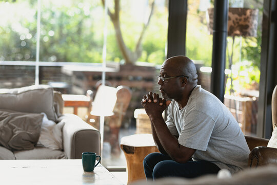 Thoughtful senior african american with folded hands man sitting on the couch