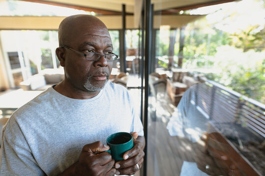 Thoughtful senior african american man pouring cup of coffee and looking at the window