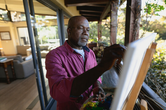 Senior african american man on sunny balcony painting a picture