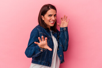 Young caucasian woman isolated on pink background upset screaming with tense hands.