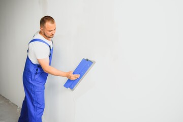The builder carefully corrects the irregularities of the wall with a trowel. Builder in work...