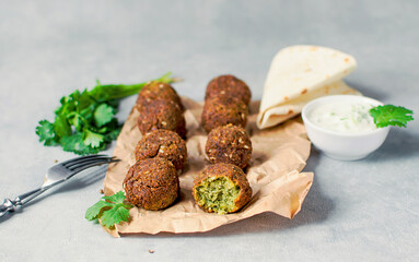 Fresh falafel balls on a black gray background with yoghurt sauce.
