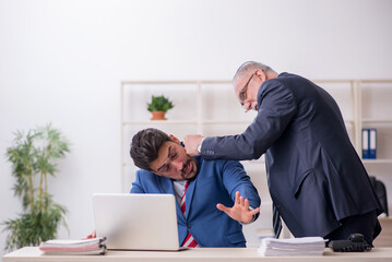 Old boss and young male employee in bullying concept