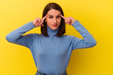Young caucasian woman isolated on yellow background focused on a task, keeping forefingers pointing head.