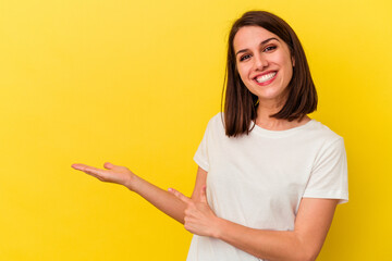 Young caucasian woman isolated on yellow background excited holding a copy space on palm.