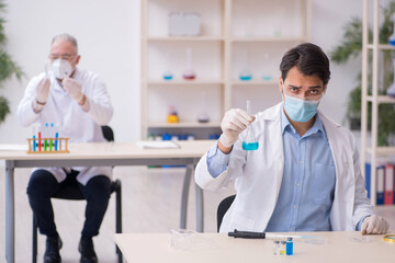Two male chemists working at the lab during pandemic