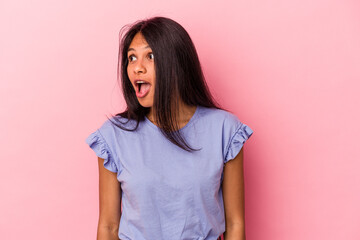 Young latin woman isolated on pink background being shocked because of something she has seen.