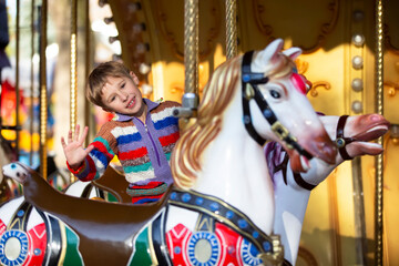 Fototapeta na wymiar Handsome little boy is riding a carousel. A child on a horse carousel.