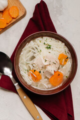 Homemade chicken soup with noodles and carrot on white background.