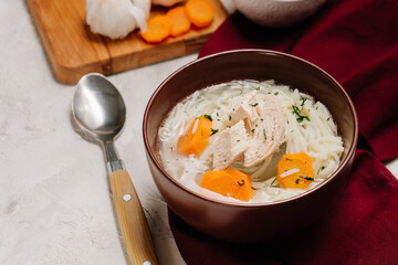 Homemade chicken soup with noodles and carrot on white background.