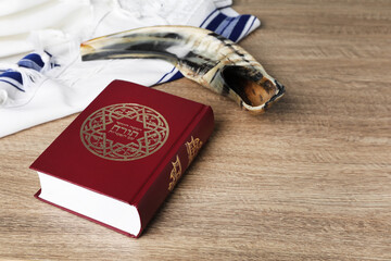 Torah book with text in Hebrew near Shofar and Tallit on wooden table. Rosh Hashanah holiday...