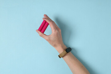 Hand holds aa batteries on blue background