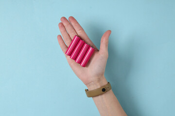 Hand holds aa batteries on blue background