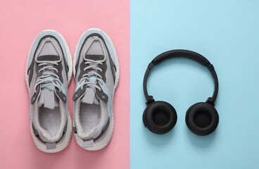 Sports shoes and headphones on blue-pink pastel background. Fitness concept. Top view. Minimalism