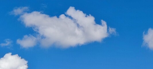 Small clouds in the clear blue sky. A summer sunny day against the backdrop of a clear blue sky, small white cumulus clouds are falling. Clouds come in various shapes and sizes.