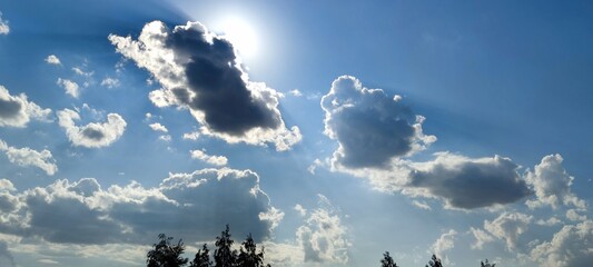The sun peeps out from behind one white cloud. Summer sunny day against the blue sky white cumulus...