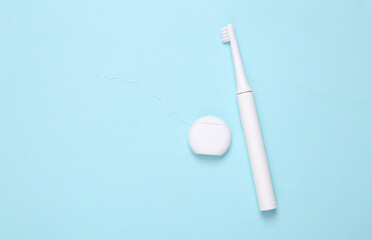 Toothbrush with dental floss on a blue background. Dental care concept, minimalism