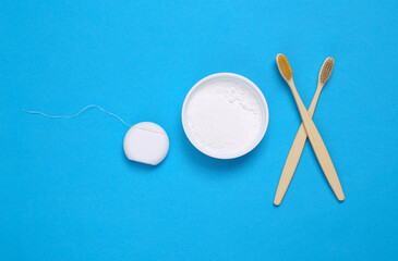 Eco Toothbrushes, tooth powder and dental floss on blue background. Dental care time