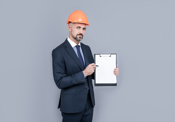 architect man in businesslike suit and hardhat showing clipboard, copy space, result