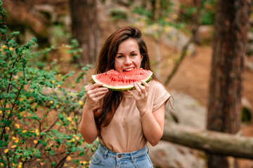 A young woman eats a watermelon outside