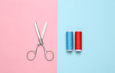 Skeins of colored thread and scissors on a blue-pink pastel background