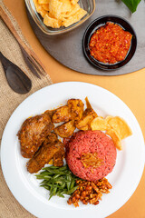 nasi lemak with dragon fruit rice served with chicken rendang and spicy sauce (sambal), sliced fresh chickpeas, small fried anchovies, roasted peanuts.