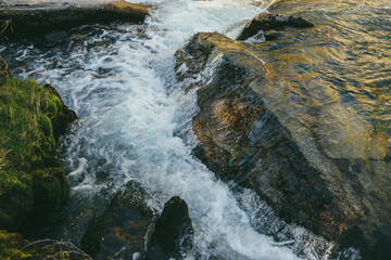 Colorful nature background with big boulder in turbulence of mountain river in sunny day. Beautiful...