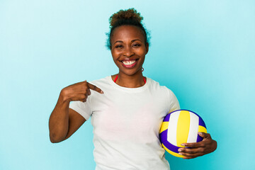 Young african american woman playing volleyball isolated on blue background person pointing by hand...