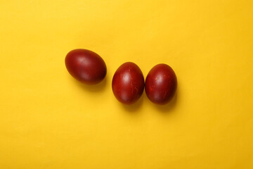 Painted red Easter eggs on yellow background. Easter minimalistic composition. Top view