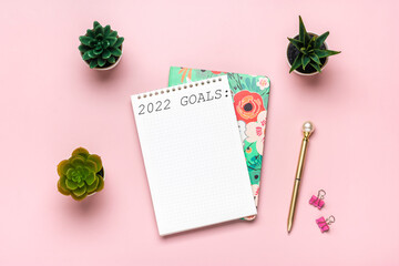 open notepad with text Goals 2022 goals, succulents, golden pen on pink background, spiral notebook on table Business, planning, education concept - Powered by Adobe