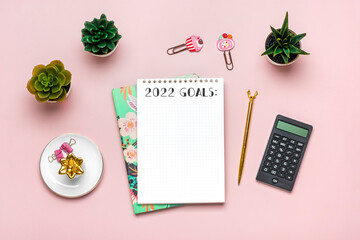 open notepad with text Goals 2022 goals, succulents, golden pen on pink background, spiral notebook on table Business, planning, education concept