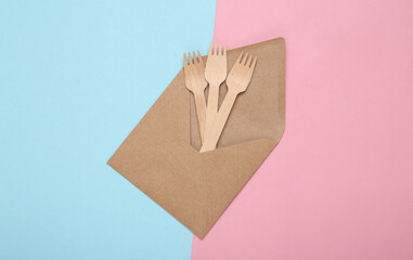 Eco concept. Craft envelope and wooden forks on blue pink pastel background