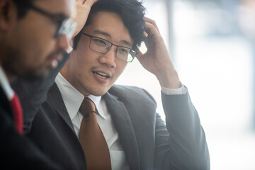young asian professional business man brianstorming on business meeting with corporate, a male black hair wearing glasses, grey suit, businessman concept. close up face.