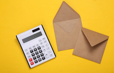 Envelopes with a calculator on yellow background. Tax payment concept