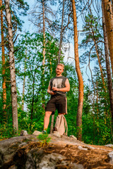 Naklejka premium Young man hiking through a pine forest with huge rocks covered with moss