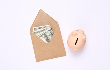 Craft envelope with one hundred dollar bills and piggy bank on white background