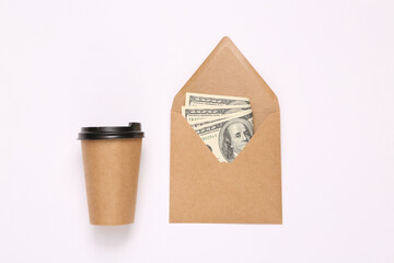 Craft envelope with one hundred dollar bills and coffee cup on white background