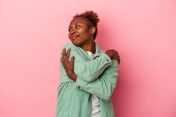 Young african american woman isolated on pink background hugs, smiling carefree and happy.